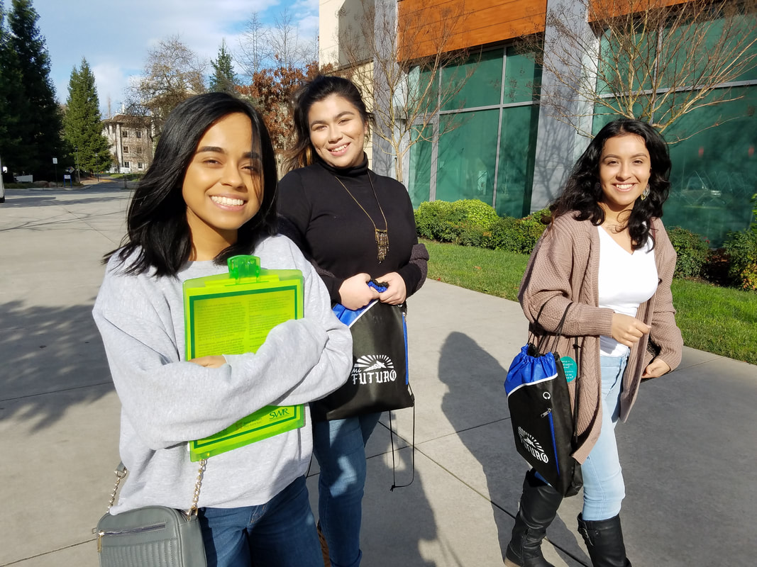 Picture of three students walking in the sunshine on the SSU campus holding folders from the health summit