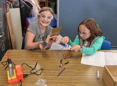 Picture of two students sitting at a table with various tools conducting an experiment.