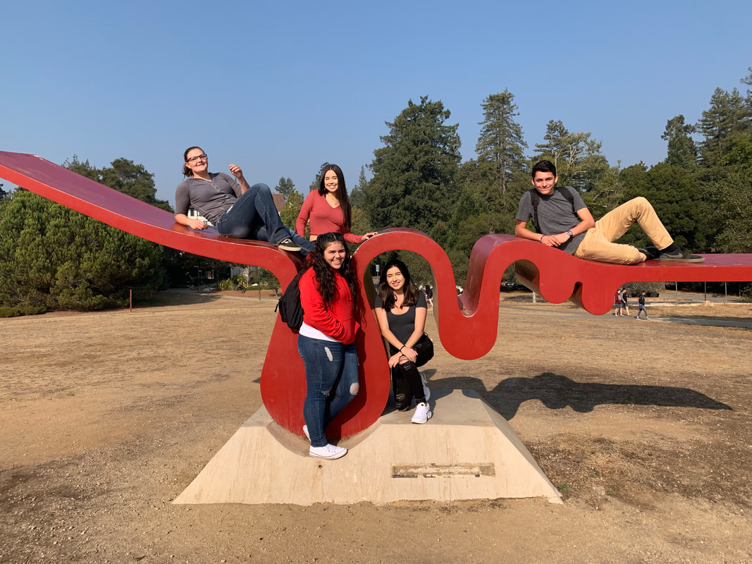 Picture of high school students resting on a large red sculpture on the UCSC campus out doors